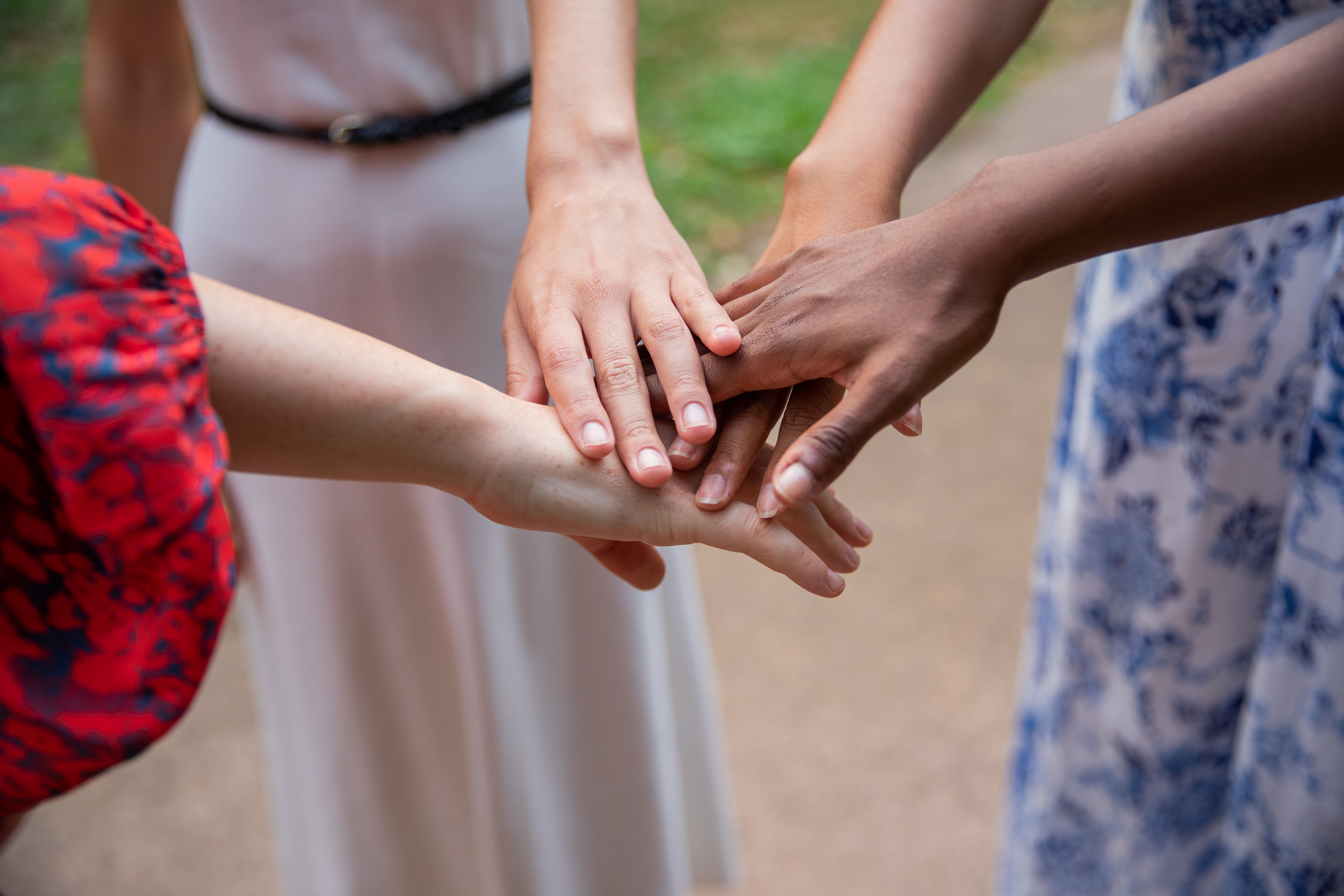 Multi-ethnic youth group at park joins hands to manifest togetherness. Friendship concept